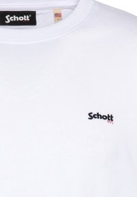T-shirt bianca in cotone con scollatura rotonda, caratterizzata da un piccolo logo ricamato "Schott NYC" in nero e rosso sul lato sinistro del petto.