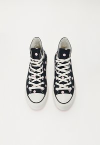 Höga sneakers i svart kanvas med rosa prickar, vita snören och gummisula. Har en vit tåkappa och texturerade detaljer.