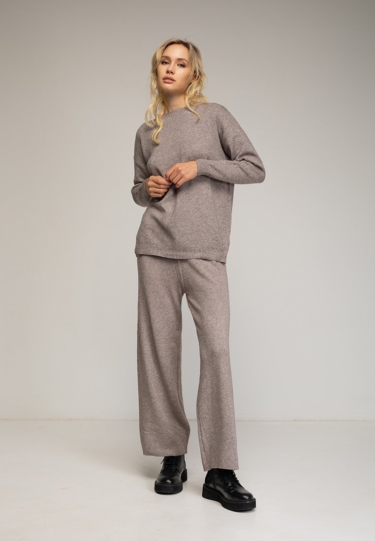 Suéter de punto marrón claro y pantalones anchos a juego, con un cuello y dobladillo acanalados, combinados con zapatos negros de suela gruesa.