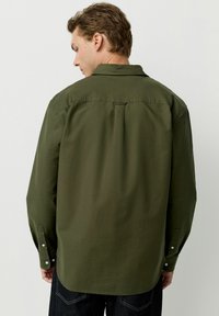 Cămașă lungă cu mânecă în culoare verde măsliniu, cu guler îndoit, pliu pe spate și manșete ajustabile. Textură fină, tiv drept și design simplu.