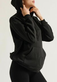 Schwarzer Kapuzenpullover mit Kängurutasche, gerippten Bündchen und strukturiertem Logodetail. Hergestellt aus weichem, komfortablem Material.