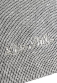Grijs ribbelbrei-stof met een zachte textuur en een geborduurd script dat "Pure Path" in een lichtere tint weergeeft.
