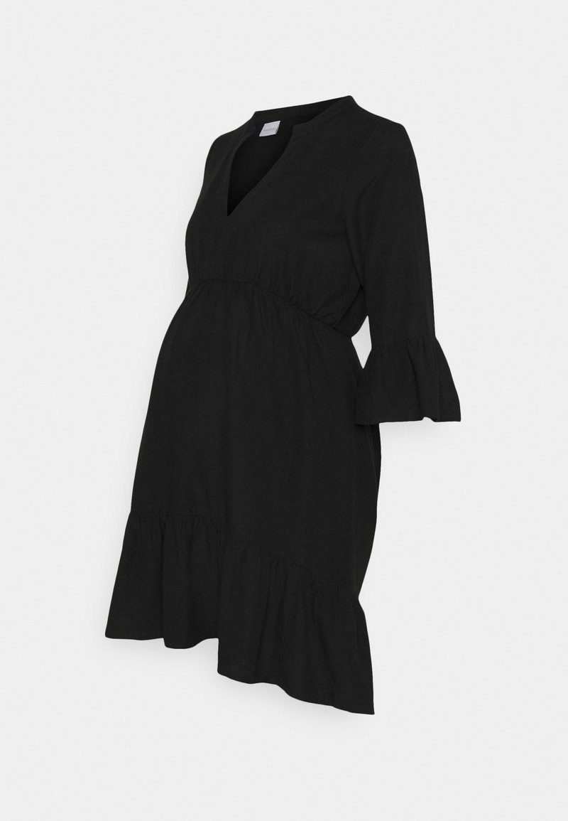 Robe de maternité noire avec un décolleté en V, des manches cloche 3/4, une taille froncée et un ourlet volanté. Fabriquée en tissu doux et léger.