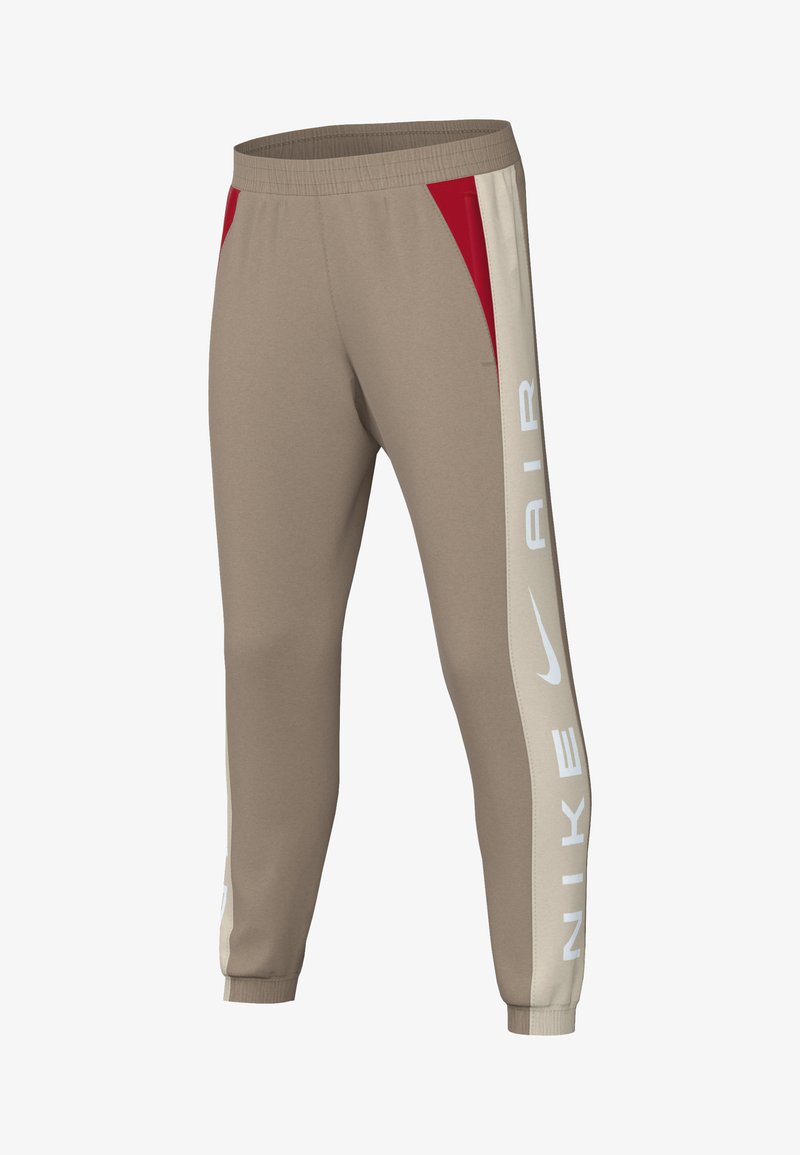 Pantalones de chándal marrones claros con un corte relajado, que cuentan con paneles laterales en rojo y crema y el texto "NIKE AIR" en blanco en un lado, con cinturilla y puños elásticos.