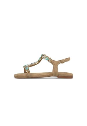 Płaska, beżowa sandała z paskiem wokół kostki, złotymi łańcuchami i ozdobami z turkusowych i przezroczystych kamieni.