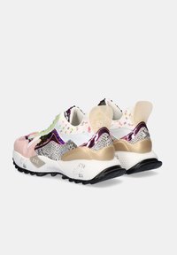 Deportivas gruesas blancas y rosas con lentejuelas multicolores, acentos de estampado animal, detalles dorados y separadores de talón translúcidos etiquetados como "EXÉ".