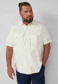 Korte mouw shirt in gebroken wit, met twee borstzakken en een knopenlijst aan de voorkant. Zachte, gestructureerde stof met een casual pasvorm.