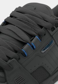 Gray sneaker featuring textured upper, thick laces, and blue eyelets. Includes a small branded detail with the word "GLOBE" on the side.