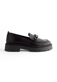 Zwarte leren loafers met een robuuste zwarte buitenzool, voorzien van een brede band en decoratieve hardware op de bovenkant. Minimalistisch ontwerp.