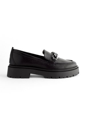 Zwarte leren loafers met een robuuste zwarte buitenzool, voorzien van een brede band en decoratieve hardware op de bovenkant. Minimalistisch ontwerp.