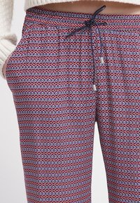 Gestreepte joggerbroek in rood, blauw en wit, met een elastische tailleband met een trekkoord en twee zijzakken.