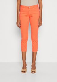 Jasnopomarańczowe krótkie dżinsy z dopasowanym krojem, wykonane z denimu. Posiadają pięć kieszeni oraz zapięcie na guzik z przodu.