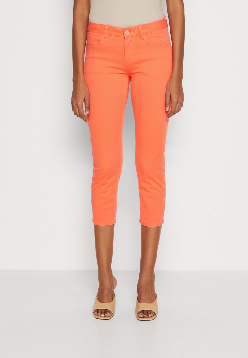 Jasnopomarańczowe krótkie dżinsy z dopasowanym krojem, wykonane z denimu. Posiadają pięć kieszeni oraz zapięcie na guzik z przodu.