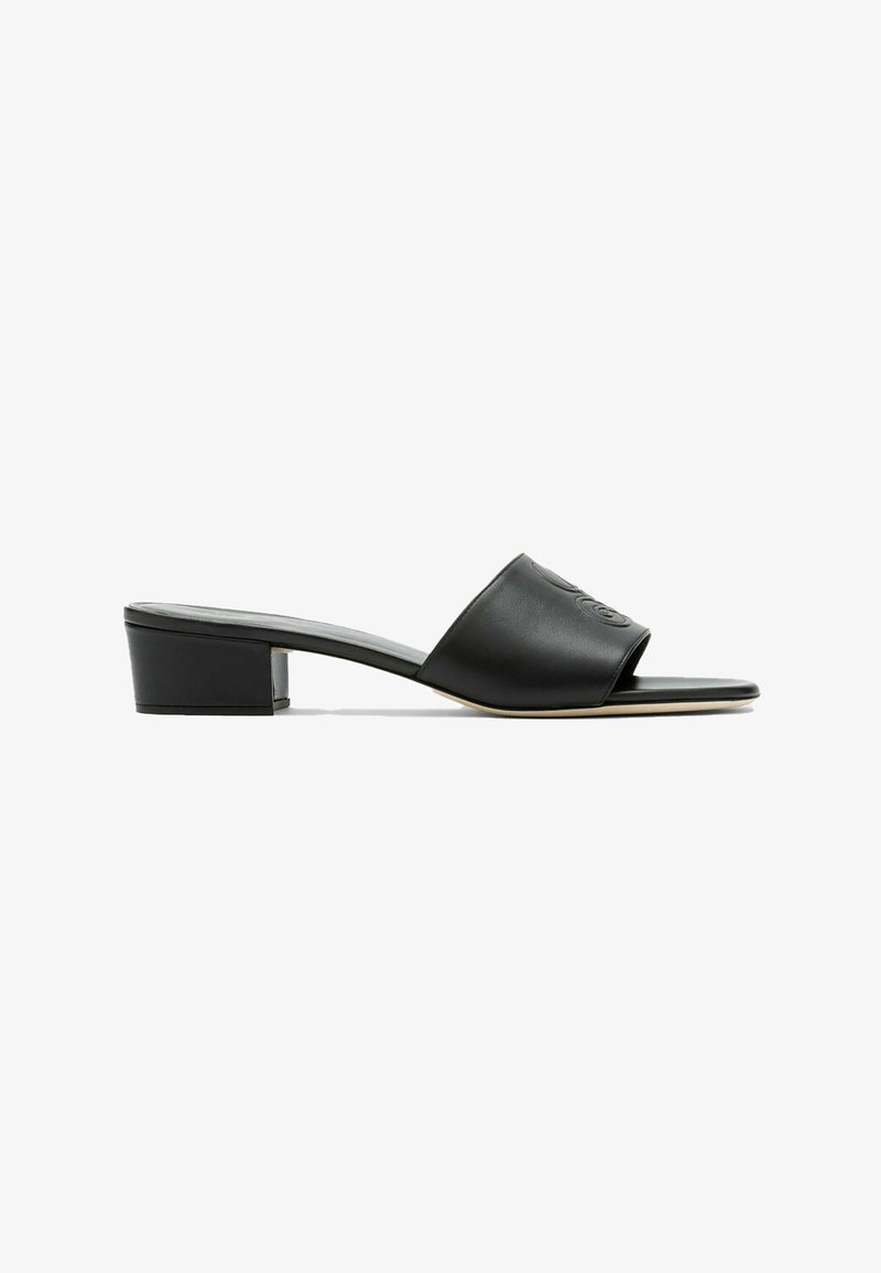 Sandale noire à bout ouvert avec talon bloc bas et large bride en cuir embossée d'un logo double-C, présentée en profil latéral.