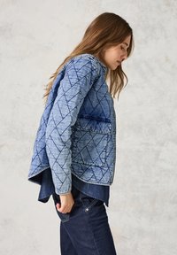 Vaatteet denim takki eri sävyissä sinistä, jonka pinnassa on timantin muotoinen kuvio. Takissa on kaulus ja sivutasku. Teksturoidusta kankaasta valmistettu rento malli.