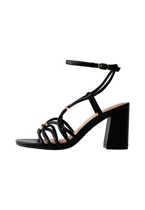 Zwarte sandaal met smalle bandjes en blokhak, met dunne bandjes en een gespsluiting. Gladde textuur met een afgeronde neus en een neutrale binnenzool.