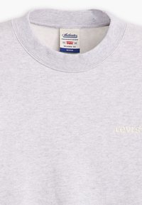 Gray sweatshirt with a round neckline, featuring a soft texture and embroidered "Levi's" logo in cream. Relaxed fit tag visible.