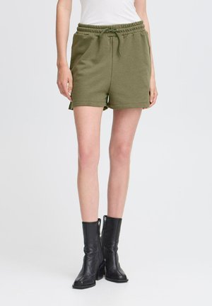 Olivgrüne Baumwollshorts mit einem elastischen Bund, Kordelzug und Seitentaschen, kombiniert mit knielangen schwarzen Lederstiefeln.
