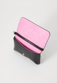 Musta nahkalompakko, jossa on vaaleanpunainen kangasvuori, napsautussuljin ja sisäinen hihna järjestelyä varten.