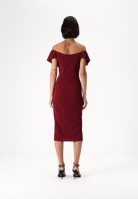 Burgundská off-the-shoulder šaty s plavkovými rukávmi, priliehavý strih, dĺžka po kolená, so zadným zipsom, skombinované s čiernymi sandálmi na opätku.