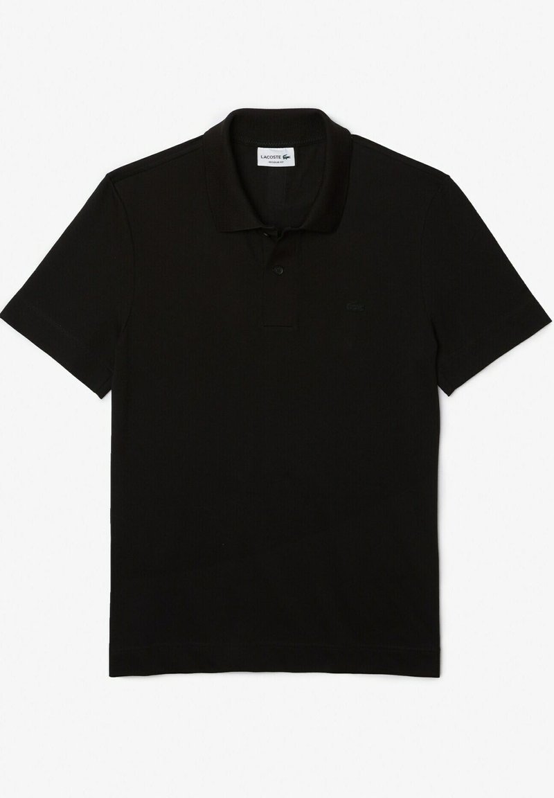 Polo noir en coton, avec un col classique, trois boutons, des manches courtes et un petit logo Lacoste sur la poitrine.