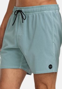 Groene zwembroek gemaakt van lichtgewicht stof, met een elastische tailleband met een zwarte koord en een RVCA-logo label aan de zoom.