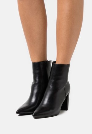 Stivaletti neri in pelle con punta affusolata e tacco a blocco, caratterizzati da un design elegante e una texture liscia. Nessun motivo o accento visibile.