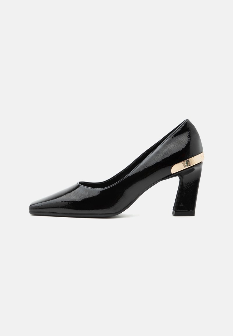 Chaussure à talon haut en cuir verni noir à bout pointu avec talon bloc et accent métallique doré à l'arrière.