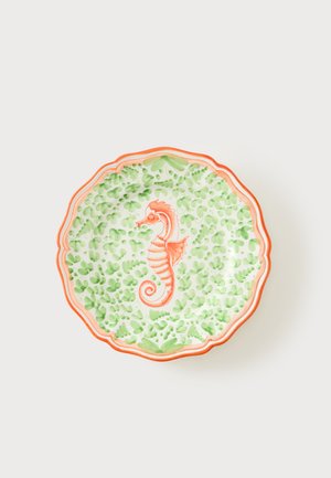 Assiette décorative à bord festonné avec un hippocampe orange au centre et un motif de feuilles vertes sur fond blanc.