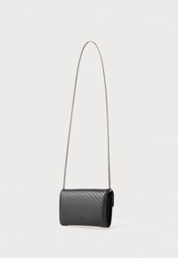 Čierna prešívaná kožená crossbody taška so vzorom chevron, strieborný reťazový popruh a kompaktný obdĺžnikový tvar. Magnetické zapínanie.