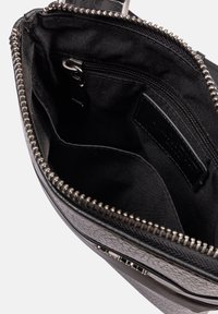 Borse in pelle nera testurizzata con zip aperta che mostra la tasca interna con zip e lo slot per schede sulla fodera in tessuto.
