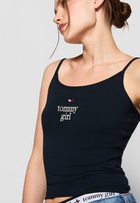Mornarsko modra bombažna majica brez rokavov s tankimi naramnicami in vezenim logotipom "tommy girl". Ima dizajn z zvezdo nad logotipom. Mehka tekstura.