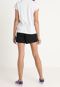 Grå t-shirt med korte ærmer, sorte shorts og lilla sneakers. Outfittet er afslappet, med et enkelt design og løs pasform.