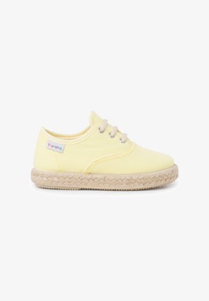 Gule kanvas sko med beige espadrille-lignende såler, rund tå og beige snørebånd. Inkluderer et lille flerfarvet logo på siden.