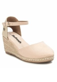 Sandalia de cuña beige con puntera cerrada, detalle de yute trenzado, tira en el tobillo y tacón texturizado. Material suave de ante sintético. Logo de la marca visible en la plantilla.