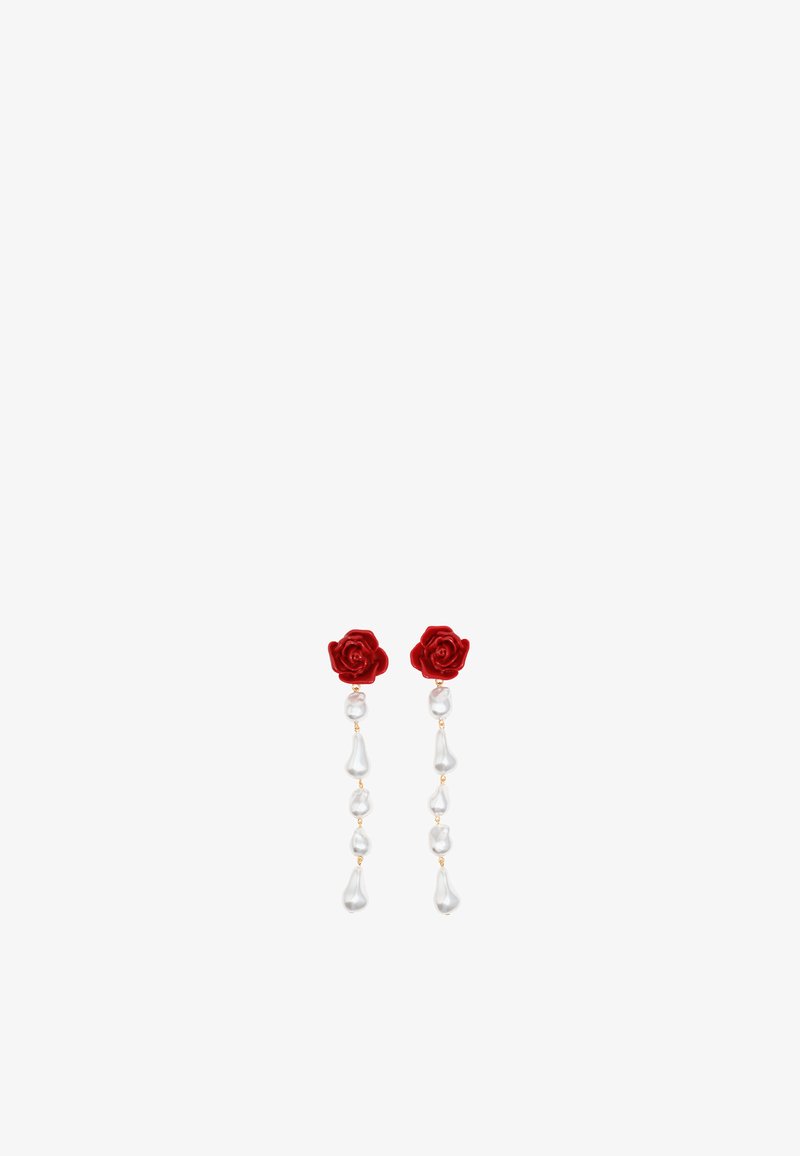 Pendientes en forma de rosa roja con perlas de imitación en forma de lágrima que cuelgan, sujetos por un accesorio de tono dorado, sobre un fondo blanco.