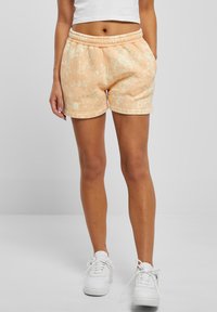 Ferskenfargede tie-dye shorts laget av myk tekstil, med elastisk midjebånd og glatt overflate, med sidelommer og hvite sømmer.