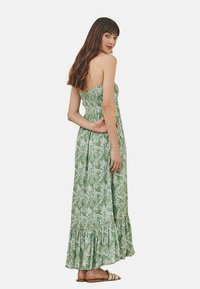 Vestido maxi verde con diseño sin tirantes, que presenta un patrón de hojas, corsé fruncido y un dobladillo con volantes. Tejido ligero, hasta el tobillo.
