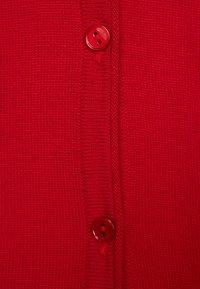 Cardigan rosso a maglia con una texture liscia, due bottoni rossi sul davanti e dettagli in costina sul colletto e sulla patta.