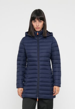 Navy pufferjack met horizontale stiksels, ritssluiting aan de voorkant en een verstelbare capuchon. Kenmerkend zijn de oranje accenten en het slanke, verlengde ontwerp.