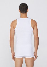 Débardeur blanc sans manches en coton lisse, au design ajusté, avec un col rond et sans motifs ni éléments de quincaillerie visibles.