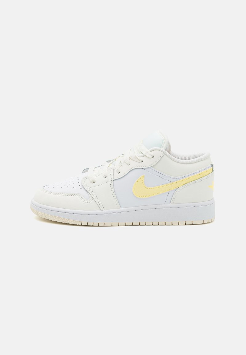 White leather sneaker with yellow accents, round toe, perforated toe box, flat laces, cushioned collar, and textured rubber sole.