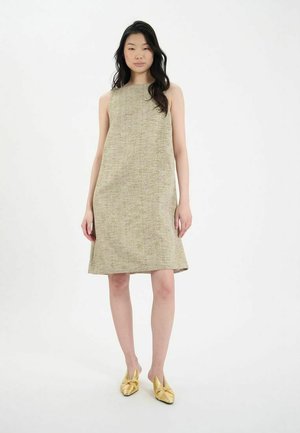 Robe chemise beige texturée avec un col haut et une silhouette évasée, associée à des ballerines métalliques dorées. Design simple, sans motifs.