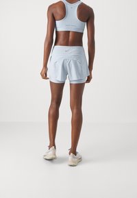 Hellblaues Sporttanktop und Shorts mit einer figurnahen Passform, glatter Textur und reflektierendem Logo-Detail auf den Shorts.