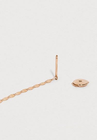 Guldtonet snoet kædeørering med en stud bagbeklædning og cirkulær lås. Glat tekstur med en reflekterende overflade.