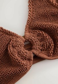 Brown textured knit bikini top with ruched fabric details and gathered cups on a neutral background.