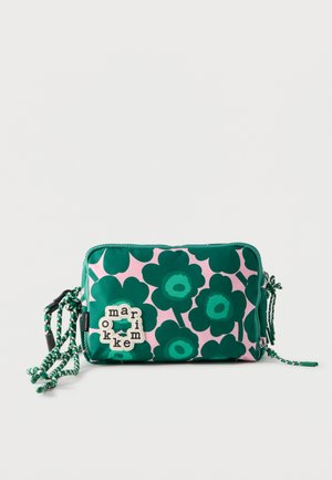 Petit sac rectangulaire porté en bandoulière avec un motif floral vert foncé sur fond rose et une sangle tressée verte et blanche.