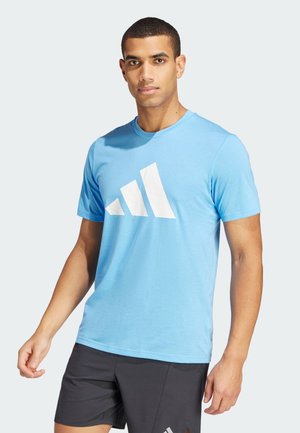 Camiseta de algodón azul con un gran logo triangular blanco en el pecho. Mangas cortas, cuello redondo y un corte relajado.
