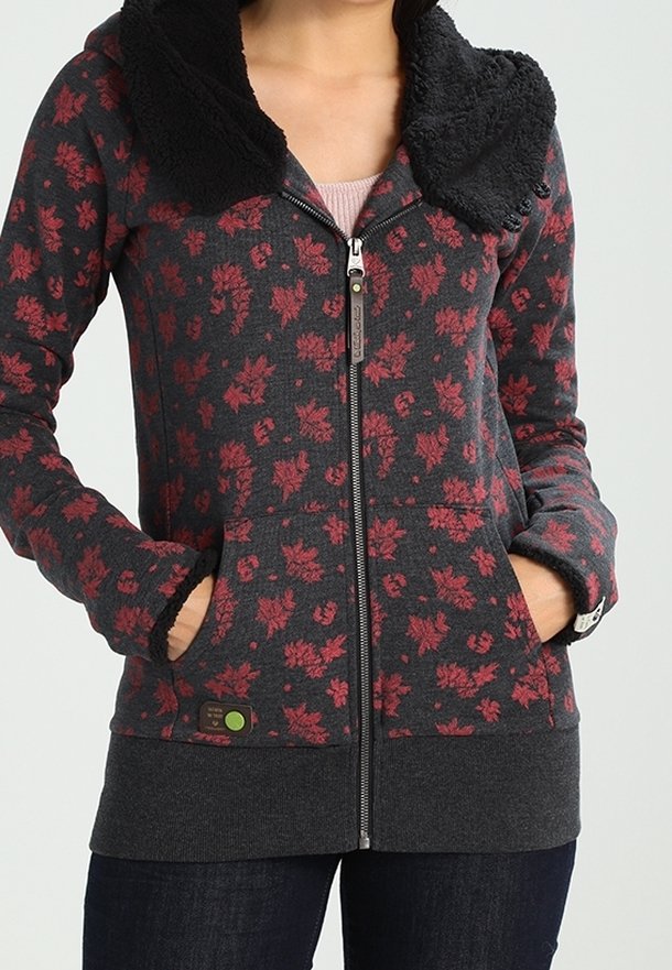 Dames zip-up hoodie in donkergrijs met een rood bloemenpatroon. Voorzien van een zwarte fuzzy kraag, twee voorzakken en geribde manchetten. Effen zoom.