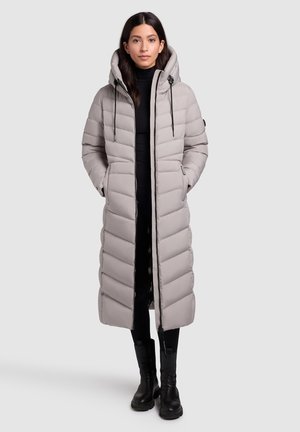 Manteau long matelassé avec un col haut et une capuche. Tissu gris clair avec un motif en chevrons, doté de poches latérales et d'une fermeture éclair. Accents noirs.